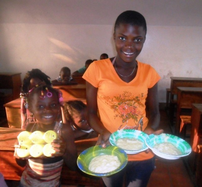 Older orphaned girl helping to serve meal during kids retreat