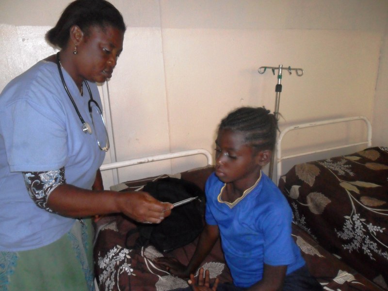 Florence checks the temperature of a child ill with malaria