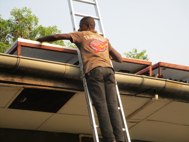 Maintenance man cleaning the solar panels using newly purchased ladder.